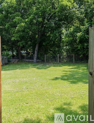 A grassy area with trees and a wooden post in the foreground.