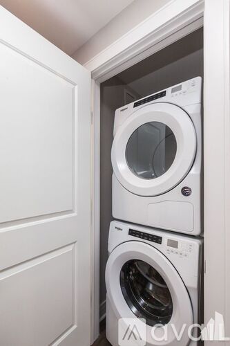 Two white washing machines in a white cabinet.