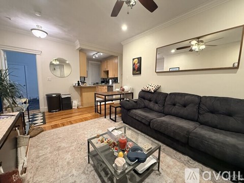 A living room with a black sofa and a glass coffee table.