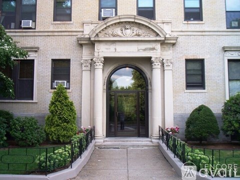 A white building with a large arched entrance and a black fence.
