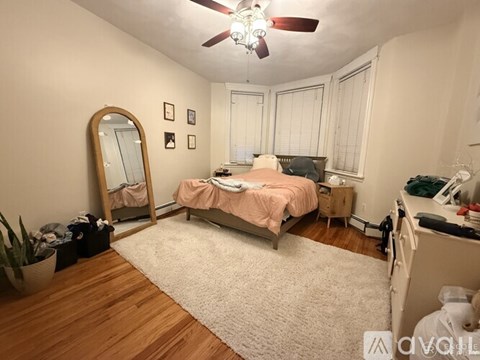 A bedroom with a bed, dresser, mirror, and a ceiling fan.