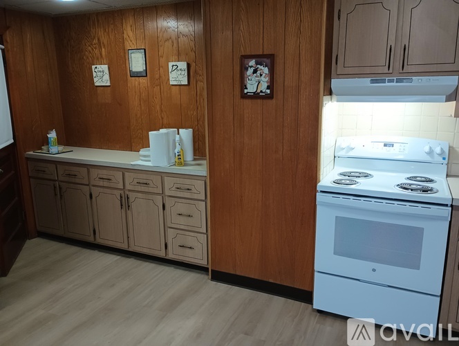 A kitchen with wooden cabinets and a white stove top oven.