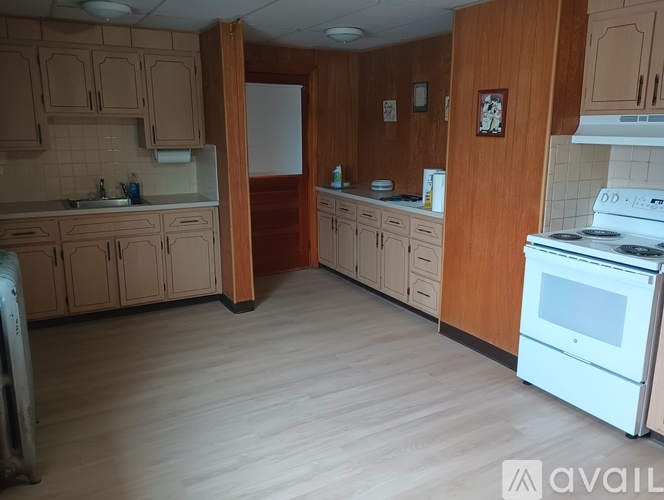 A kitchen with wooden cabinets and a white stove.
