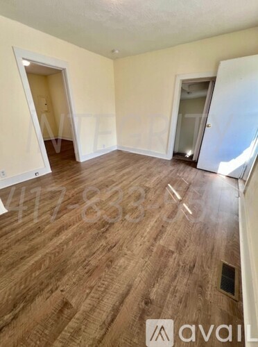 A room with wooden flooring and two doors, one of which is open.