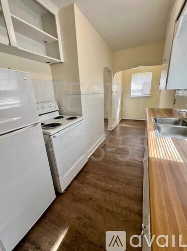A kitchen with white appliances and wooden floors.