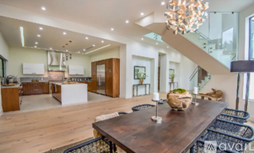 A modern kitchen with a wooden table and a chandelier.