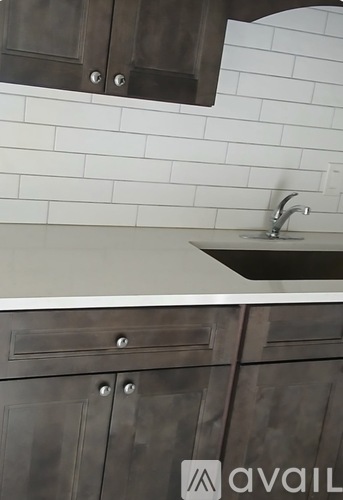 A kitchen with a white sink and a white tiled wall.