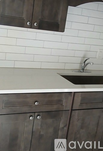 A kitchen with a white sink and a white tiled wall.