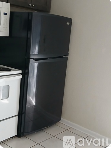 A black fridge in a kitchen with a white dishwasher.