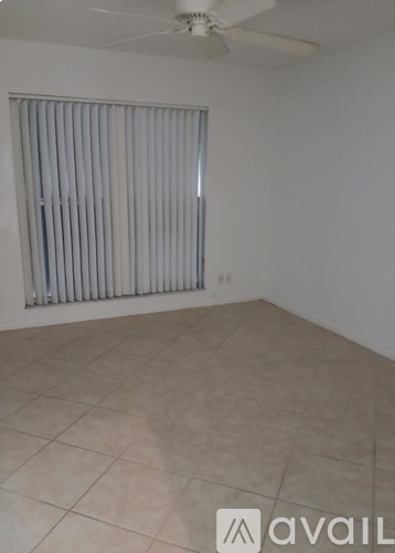 A room with a fan and a window covered with blinds.