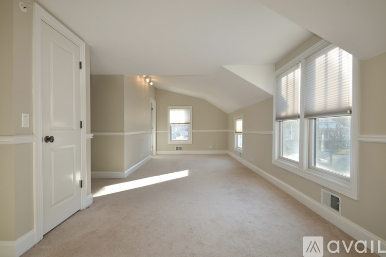 A spacious room with a door on the left and windows on the right.