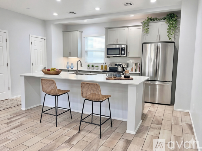 A kitchen with a white island and two chairs.