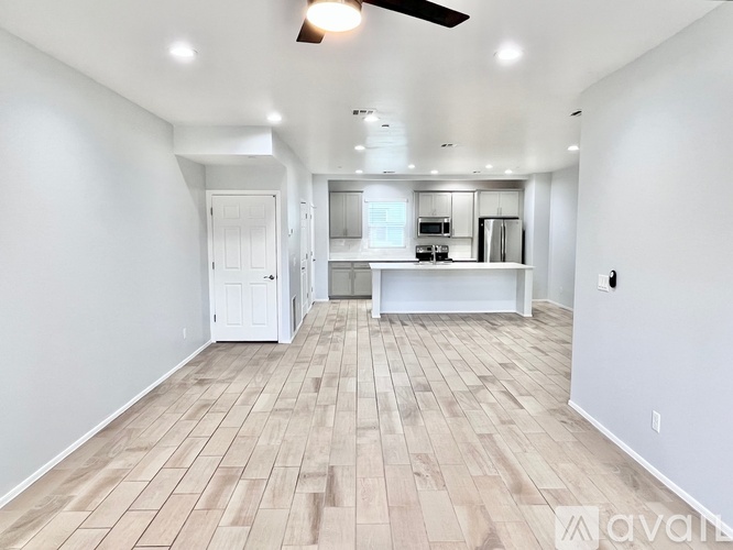 A spacious room with wooden flooring and a ceiling fan.