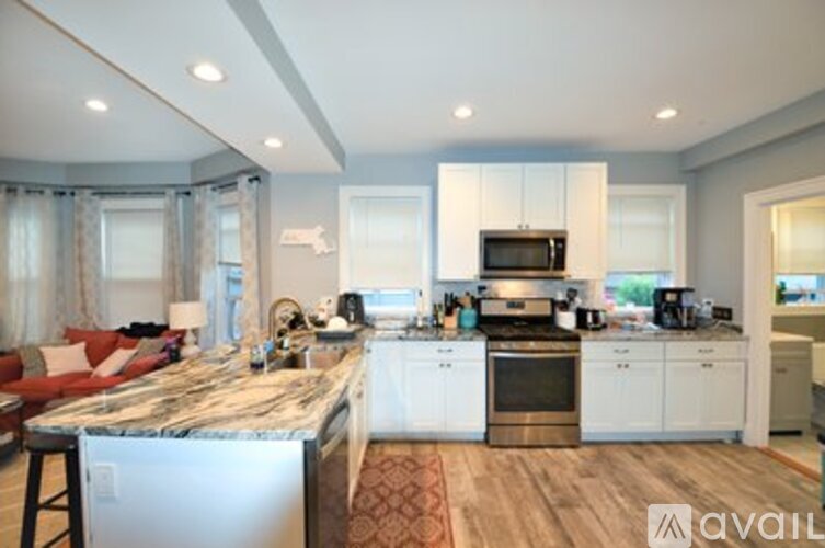 A modern kitchen with white cabinets and a marble island.