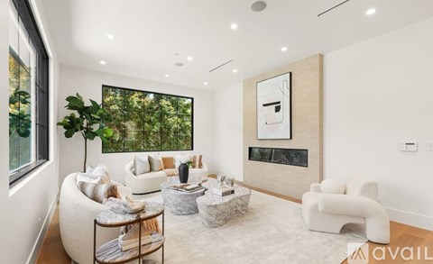 A living room with a large window, a fireplace, and a painting on the wall.