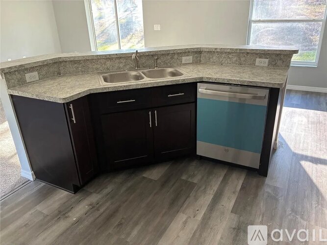 A kitchen with dark brown cabinets and a granite countertop.