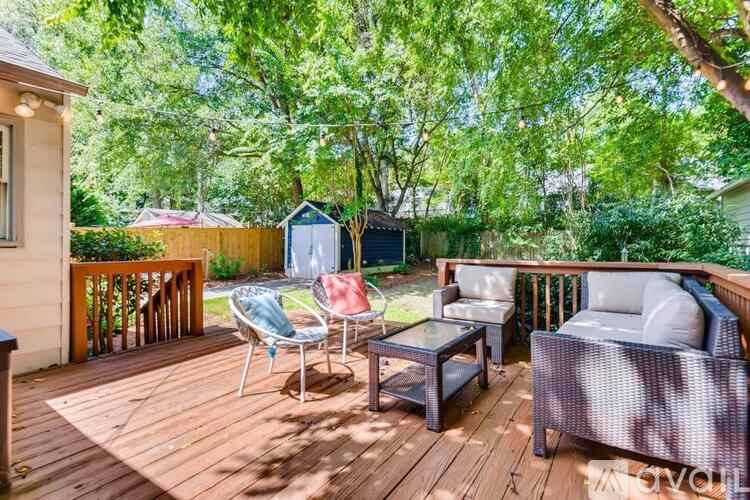 A wooden deck with a table and chairs is surrounded by trees.