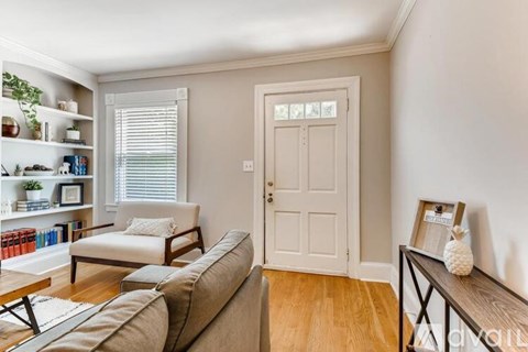 A living room with a couch, chair, and a table with a picture frame on it.