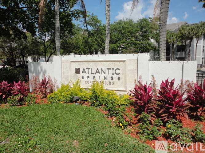 A sign that says "Atlantic Condominiums" in front of some trees.