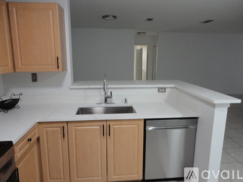 A kitchen with wooden cabinets and a stainless steel dishwasher.