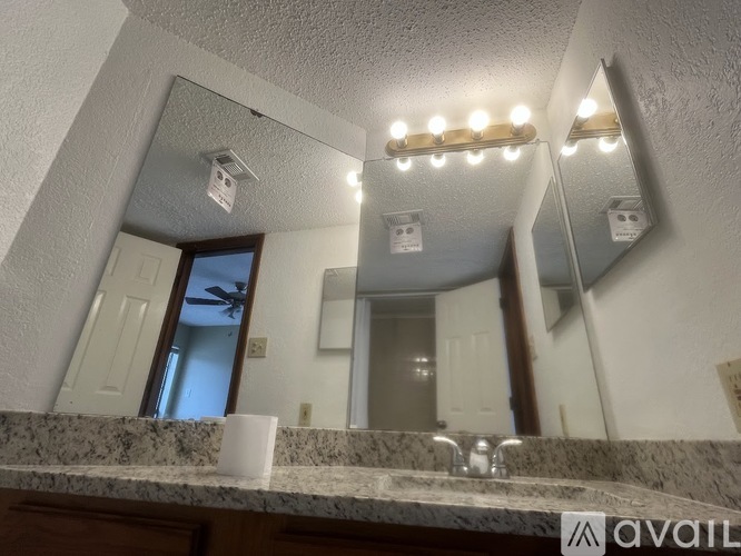 A bathroom with a marble countertop and a large mirror with lights above it.