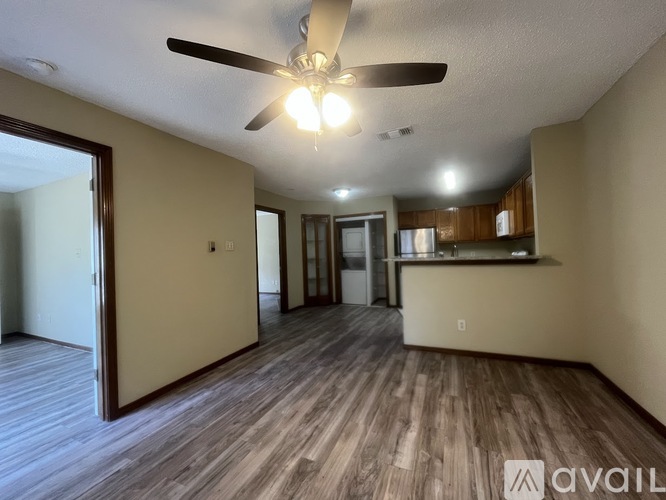A spacious room with wood flooring and a ceiling fan.