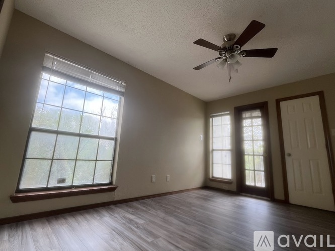 A room with a ceiling fan and a window with a view of trees.