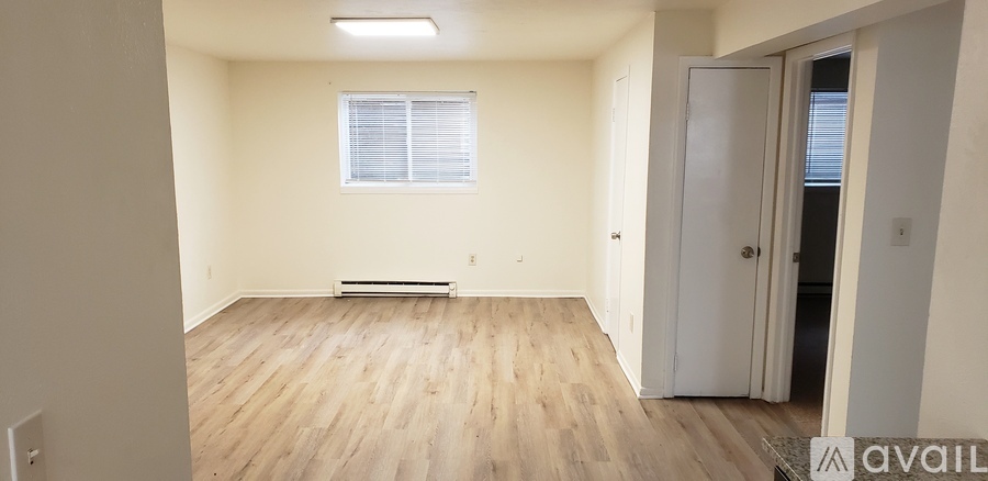 A room with wooden flooring and a window with blinds.