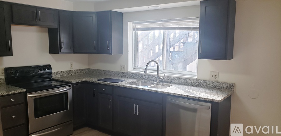 A kitchen with black cabinets and a stainless steel dishwasher.