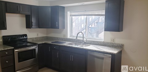 A kitchen with black cabinets and a stainless steel dishwasher.
