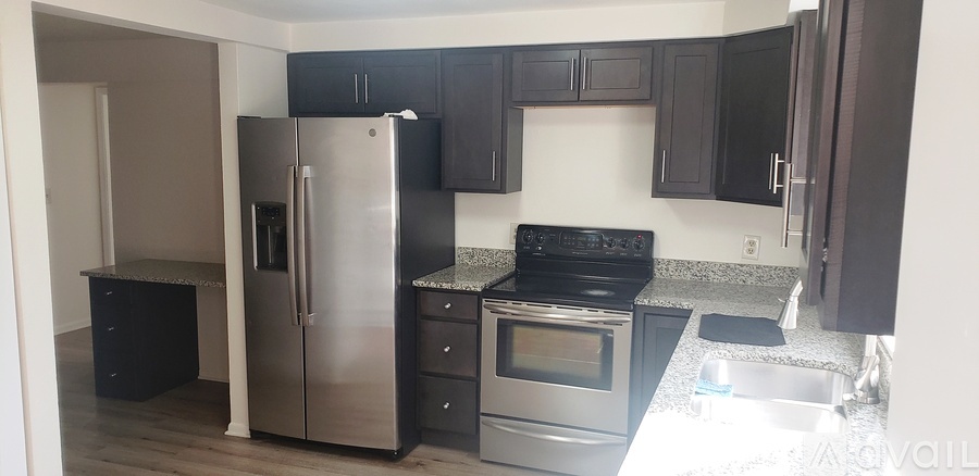 A kitchen with a stainless steel refrigerator and black cabinets.