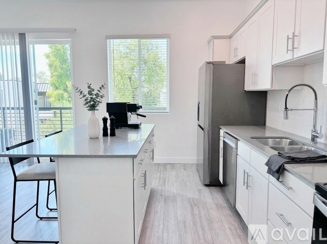 A kitchen with white cabinets and a black fridge.