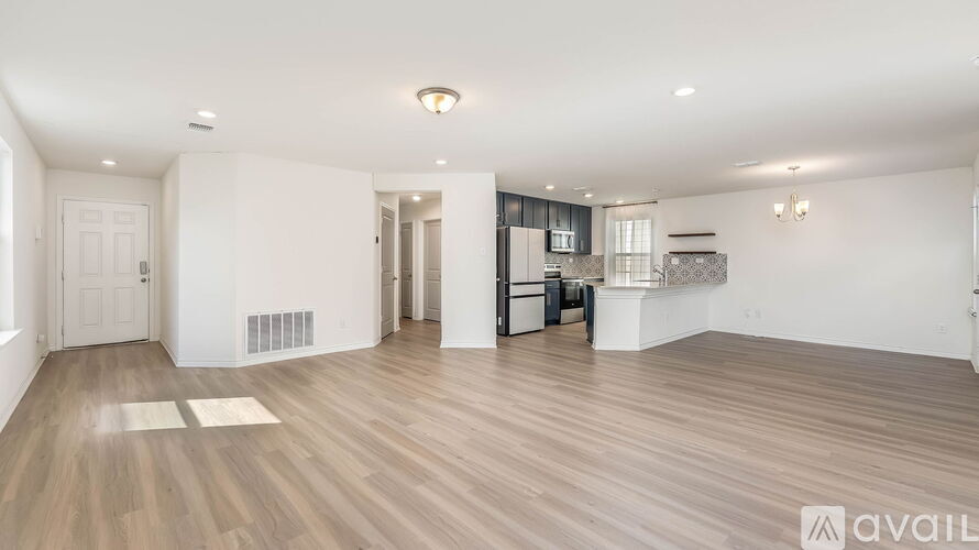 A spacious living room with wooden flooring and white walls.