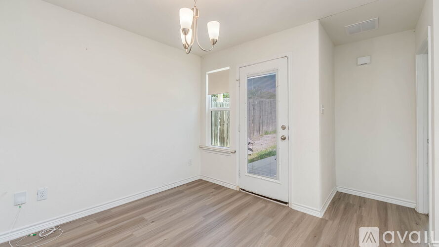 A room with a white door and a window showing a view of a fence and trees.
