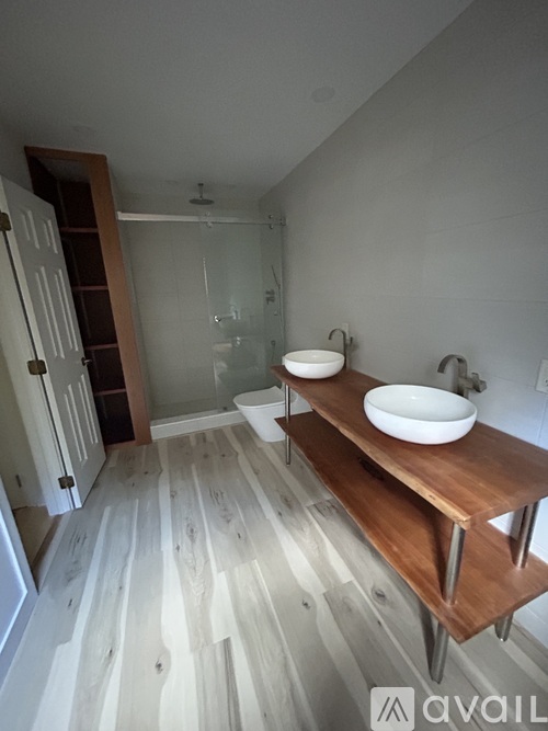 A bathroom with a wooden vanity and a walk-in shower.