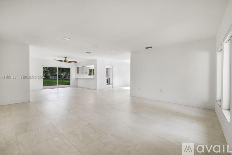 A spacious room with a fan and large windows.