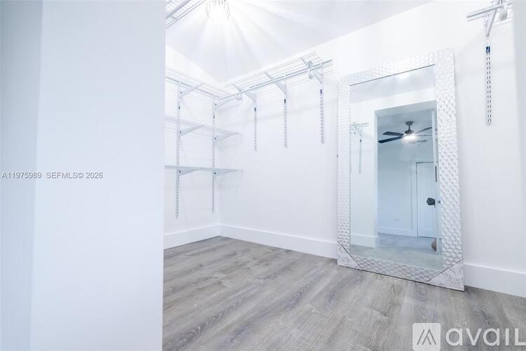 A spacious room with a mirrored wall and wooden flooring.