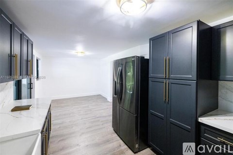 A kitchen with black cabinets and a white countertop.