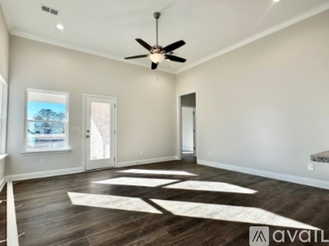A spacious room with a ceiling fan and wooden flooring.