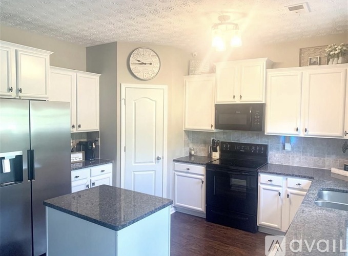 A kitchen with white cabinets and a black stove top oven.