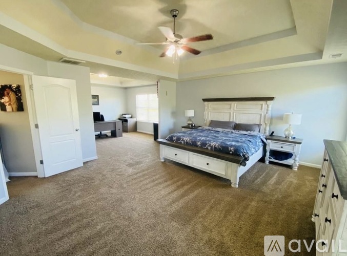 A bedroom with a large bed and a ceiling fan.