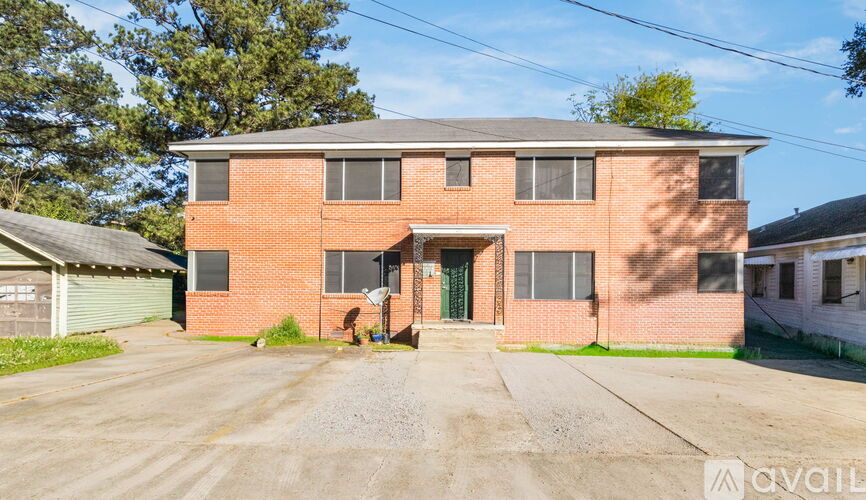 A two-story brick house with a gravel driveway in front.