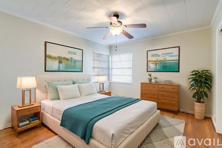 A bedroom with a bed, a ceiling fan, and a plant.