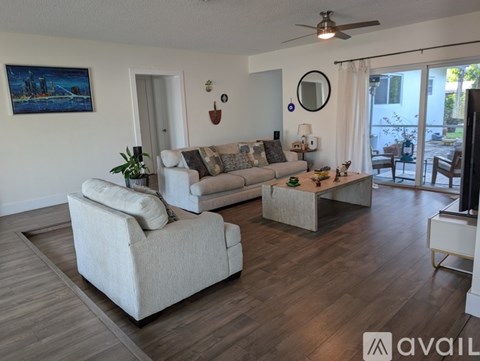 A living room with a white couch and a painting on the wall.