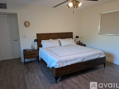 A bedroom with a large bed and a wooden nightstand.