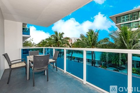 A balcony with chairs and a table overlooking a pool.