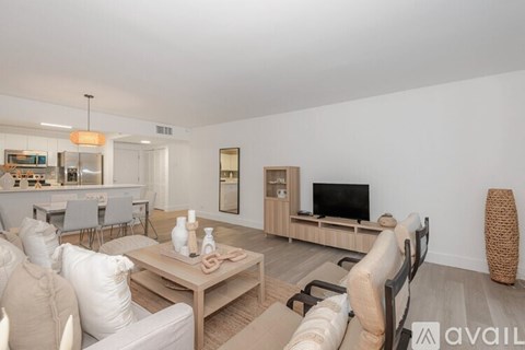A living room with a white couch, a wooden coffee table, and a television on a wooden stand.