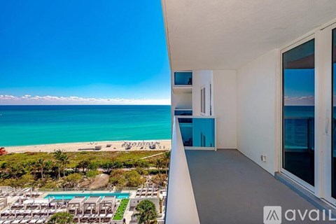 A balcony overlooks a pool and beach.