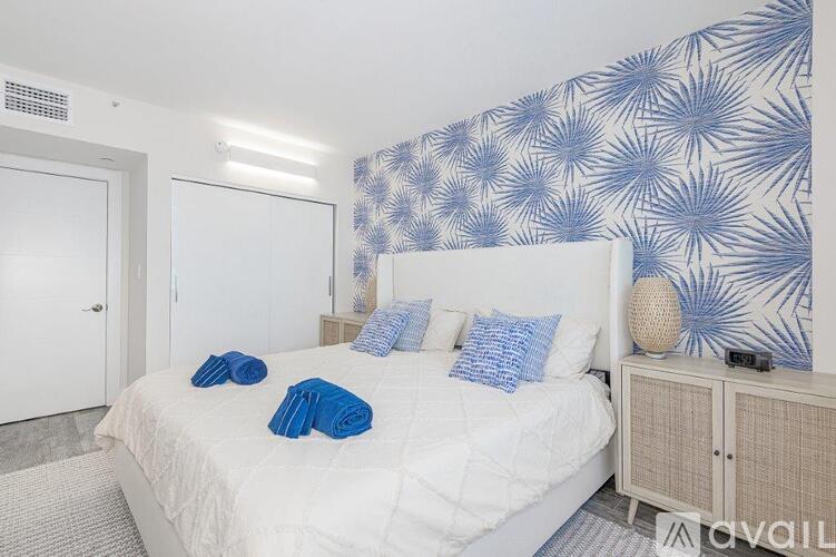 A bedroom with a white bed and blue pillows.