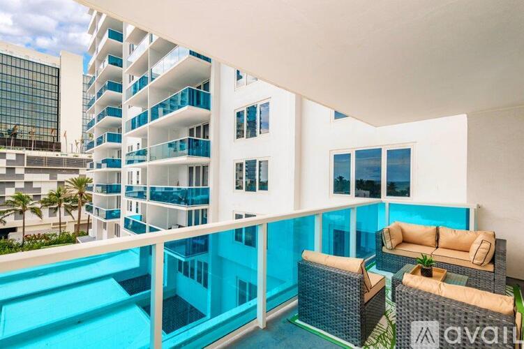 A balcony with a blue pool and white building in the background.